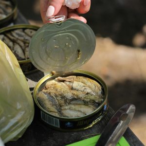 person holding clear glass jar with yellow powder